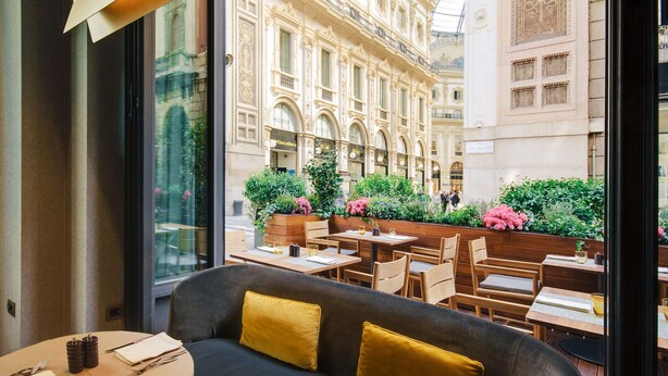 A restaurant with a view of a historic building, outdoor seating with tables and chairs, and a modern interior with a sofa and cushions. - Park Hyatt Milano (Milan)