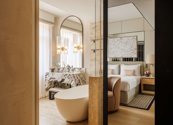 Un baño moderno con una bañera independiente, un espejo grande y un tocador con encimera de mármol.