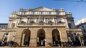 A historic building with classical architecture, featuring a central entrance with three arches, columns, and a decorative pediment.