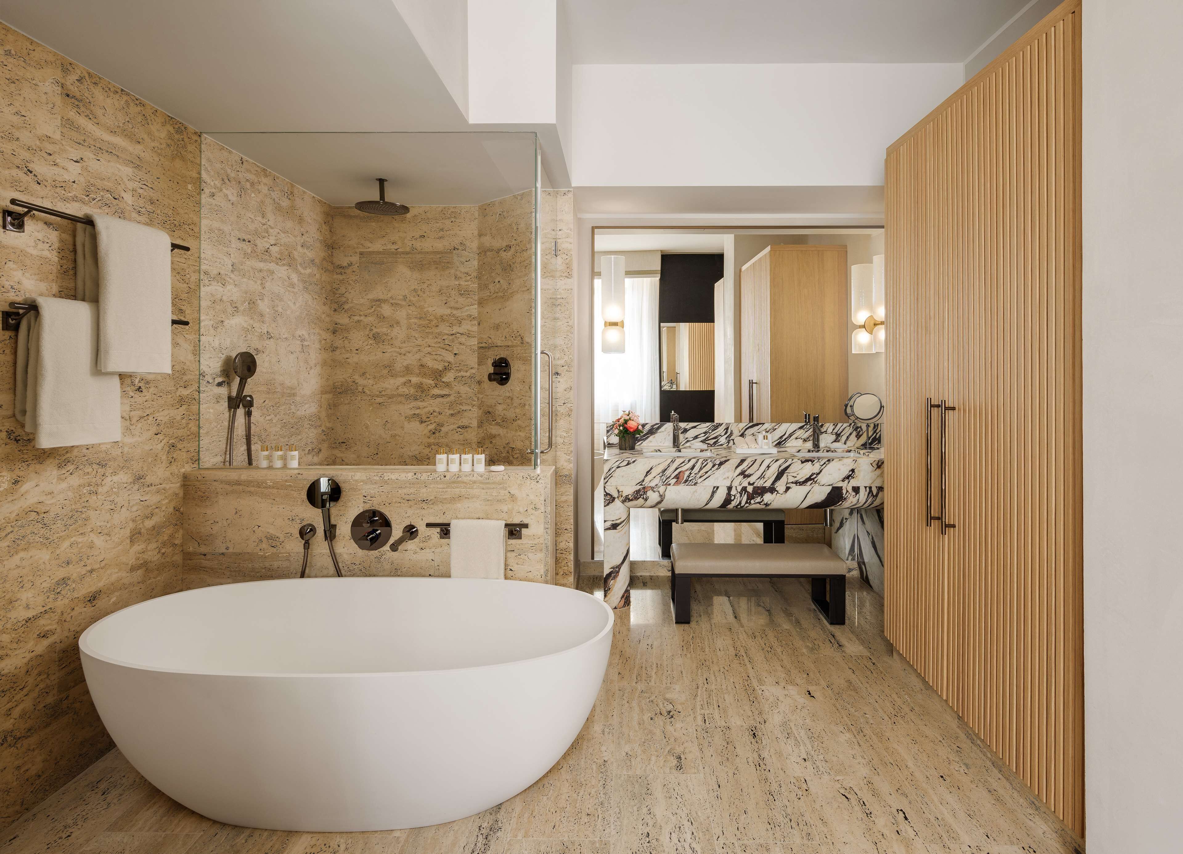 A modern bathroom with a freestanding bathtub, a glass-enclosed shower, and a wooden vanity with a marble countertop.