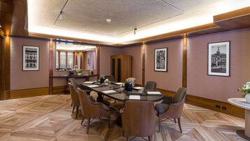 A conference room with a large table, chairs, and framed pictures on the walls.