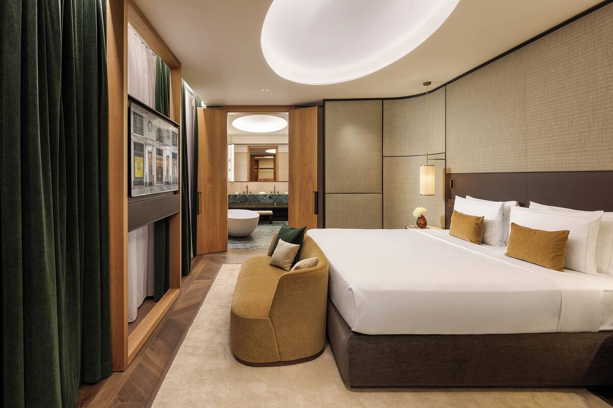 A modern hotel room with a large bed, a seating area, and a view of the bathroom.