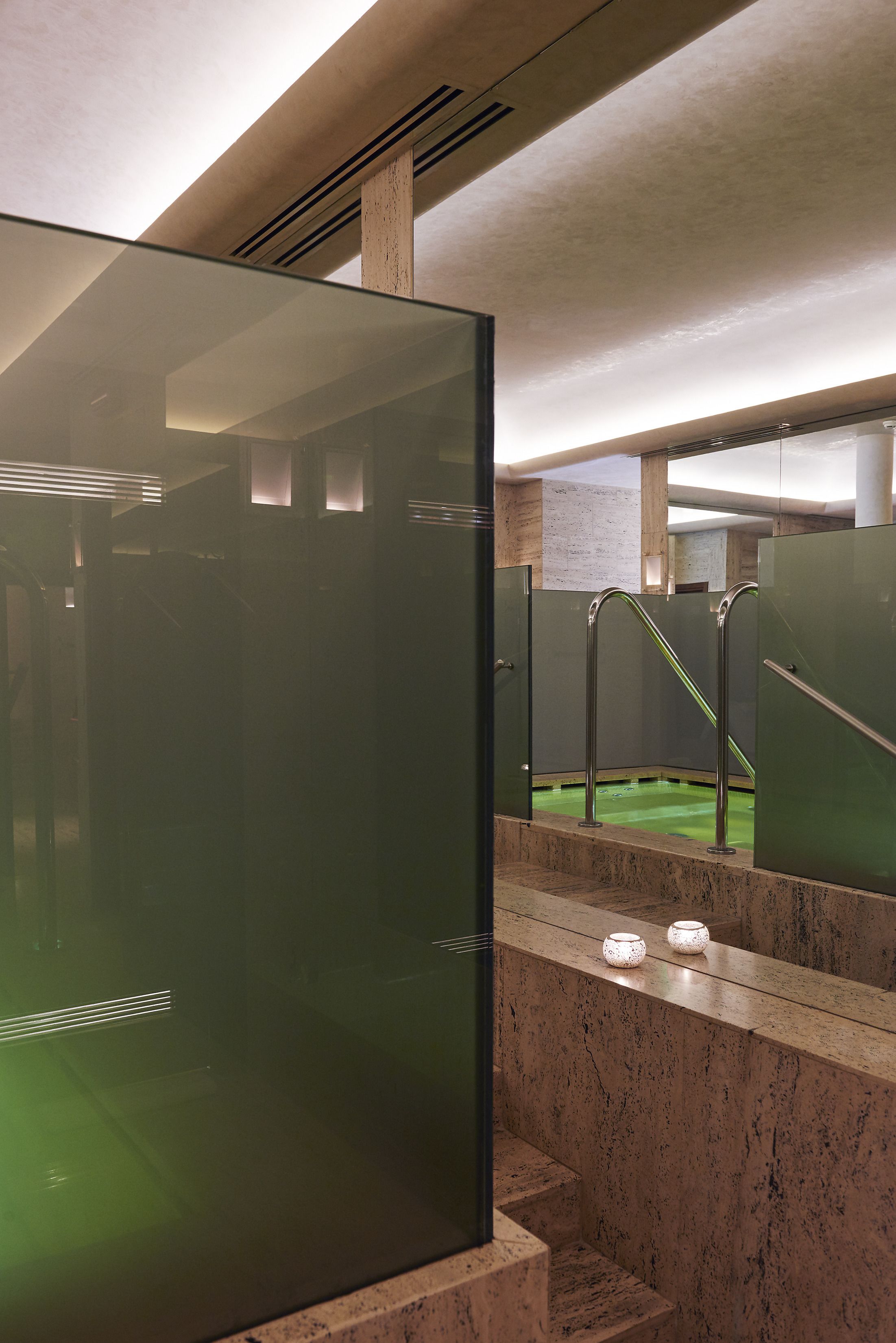 A modern bathroom with glass partitions, a green heated floor, and marble walls.