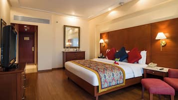 A hotel room with a bed, bedside table, lamp, and a desk with a telephone.
