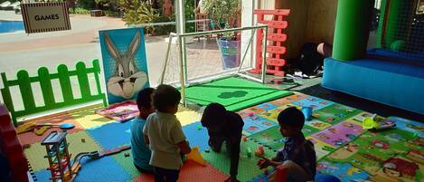 A children's play area with colorful mats, toys, and a sign labeled "GAMES".