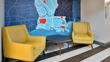 A lobby with two yellow armchairs, a dark wooden table, and a large wall map.