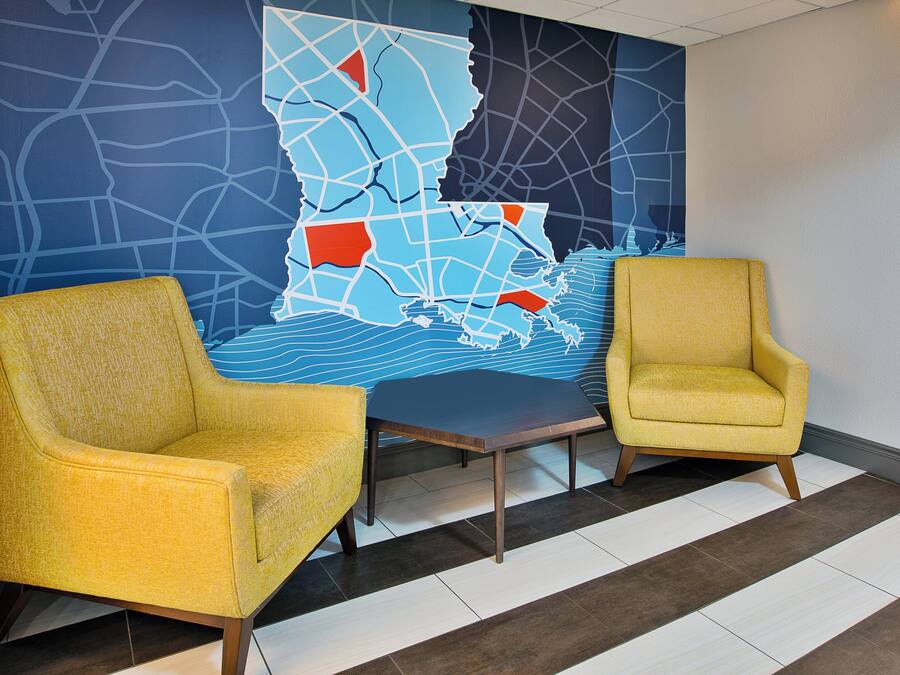 A lobby with two yellow armchairs, a dark wooden table, and a large wall map.