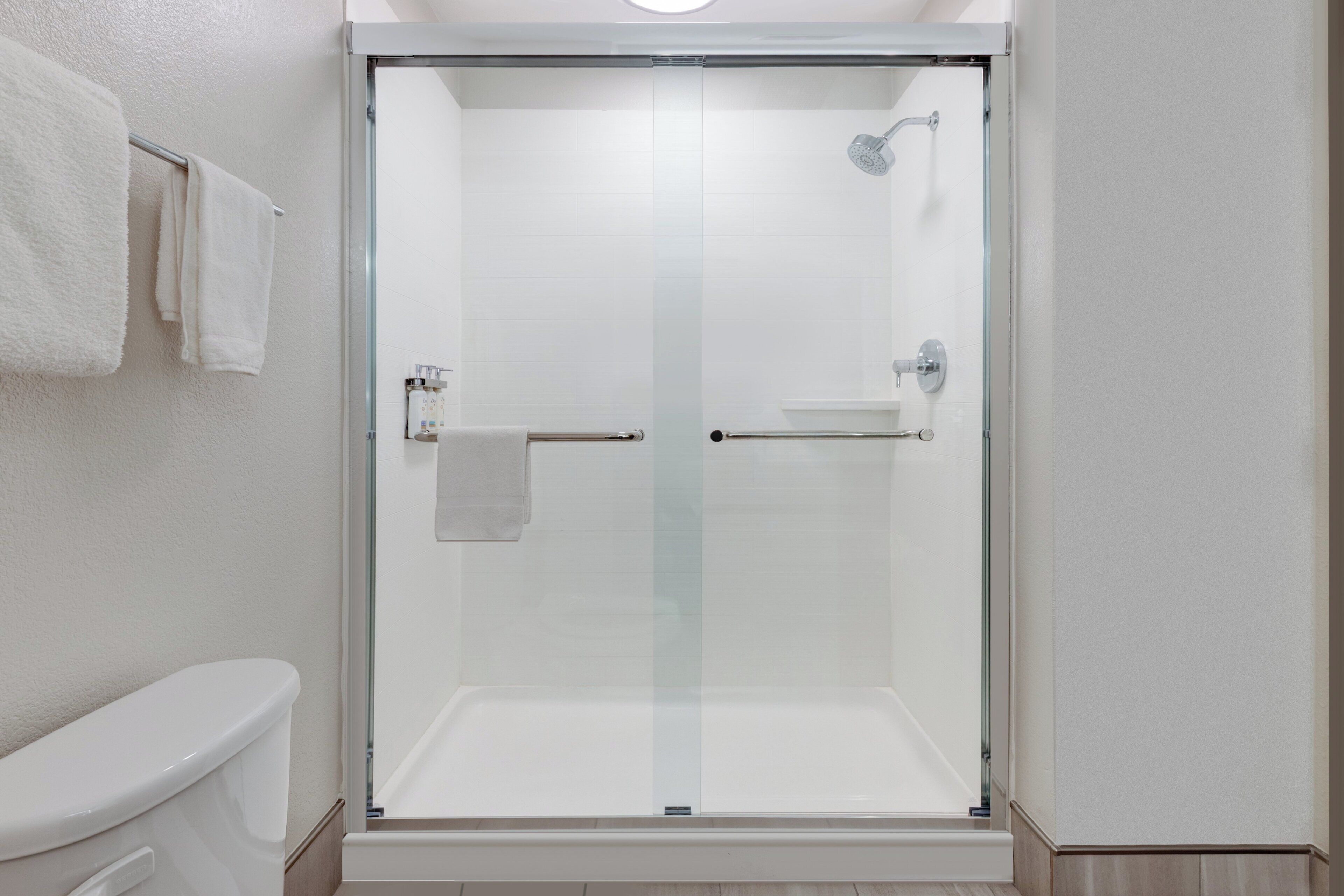 A modern bathroom with a glass-enclosed shower, a toilet, and a towel rack.