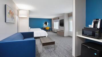 Una habitación de hotel con cama, escritorio, microondas y refrigerador.