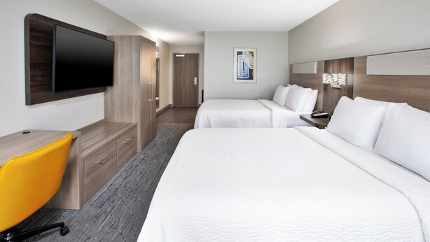 A hotel room with two beds, a desk, a chair, a TV, and a door leading to another room. - Holiday Inn Express & Suites W. Monroe by IHG (West Monroe)