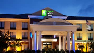 Welcome to Holiday Inn Express & Suites, featuring a central entrance with a covered walkway and warm lighting.
