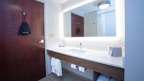 A modern bathroom with a wooden door, a white sink, a mirror, and a towel rack.