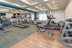 Un gimnasio con cintas de correr, elípticas y equipo de pesas.