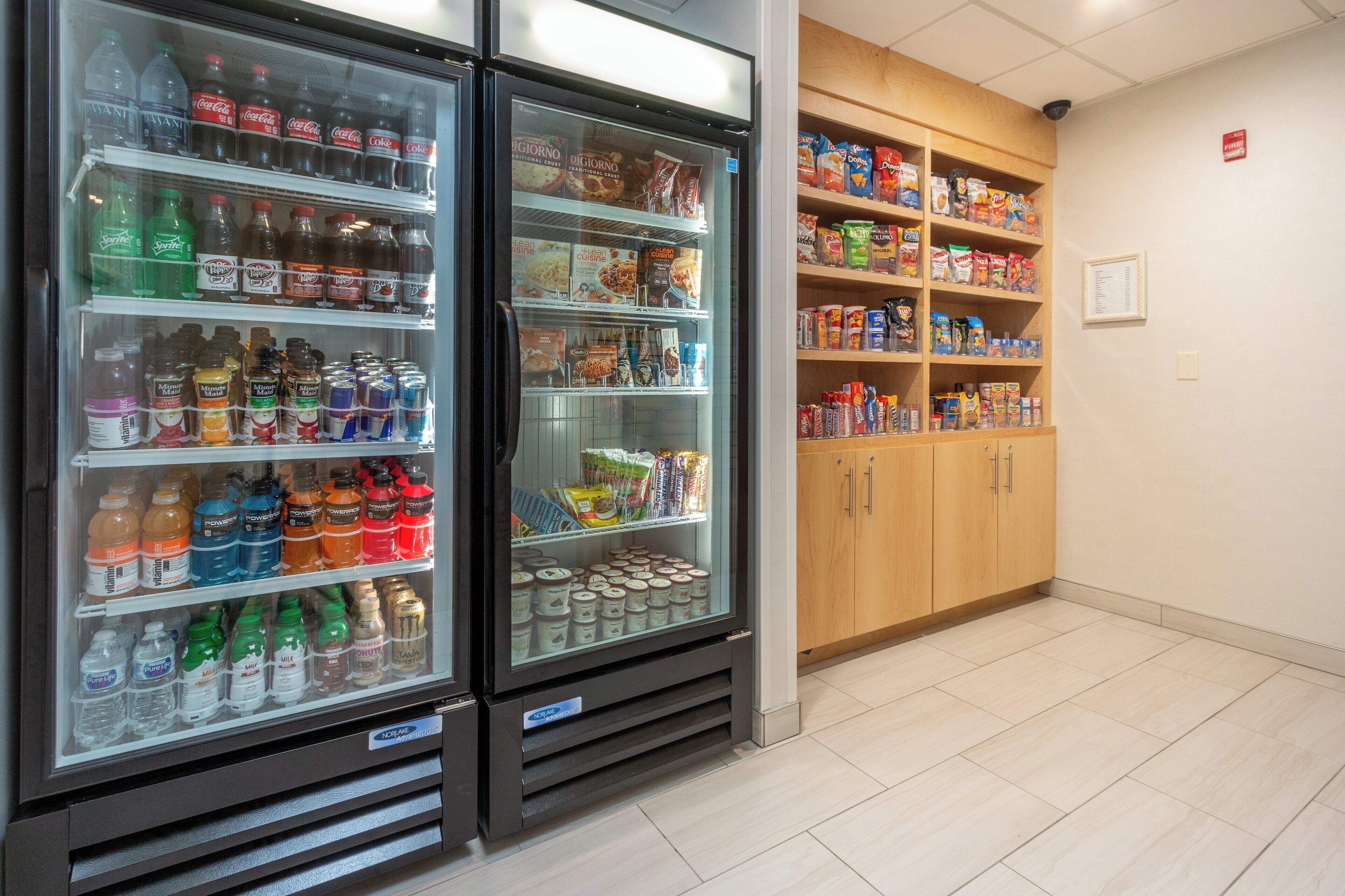 A vending machine stocked with beverages and snacks, adjacent to a shelf with packaged food items.