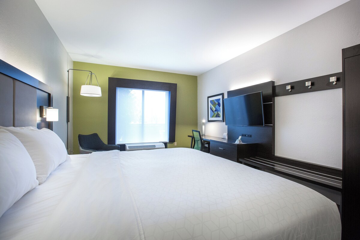 Una camera d'albergo con un letto grande, una scrivania, una sedia, un televisore e una finestra.