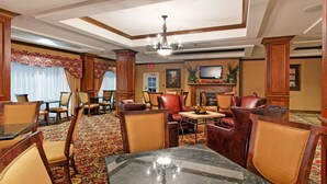 A hotel lobby with a chandelier, leather chairs, a fireplace, and a television. - Holiday Inn Express Hotel & Suites Tupelo by IHG (Tupelo)