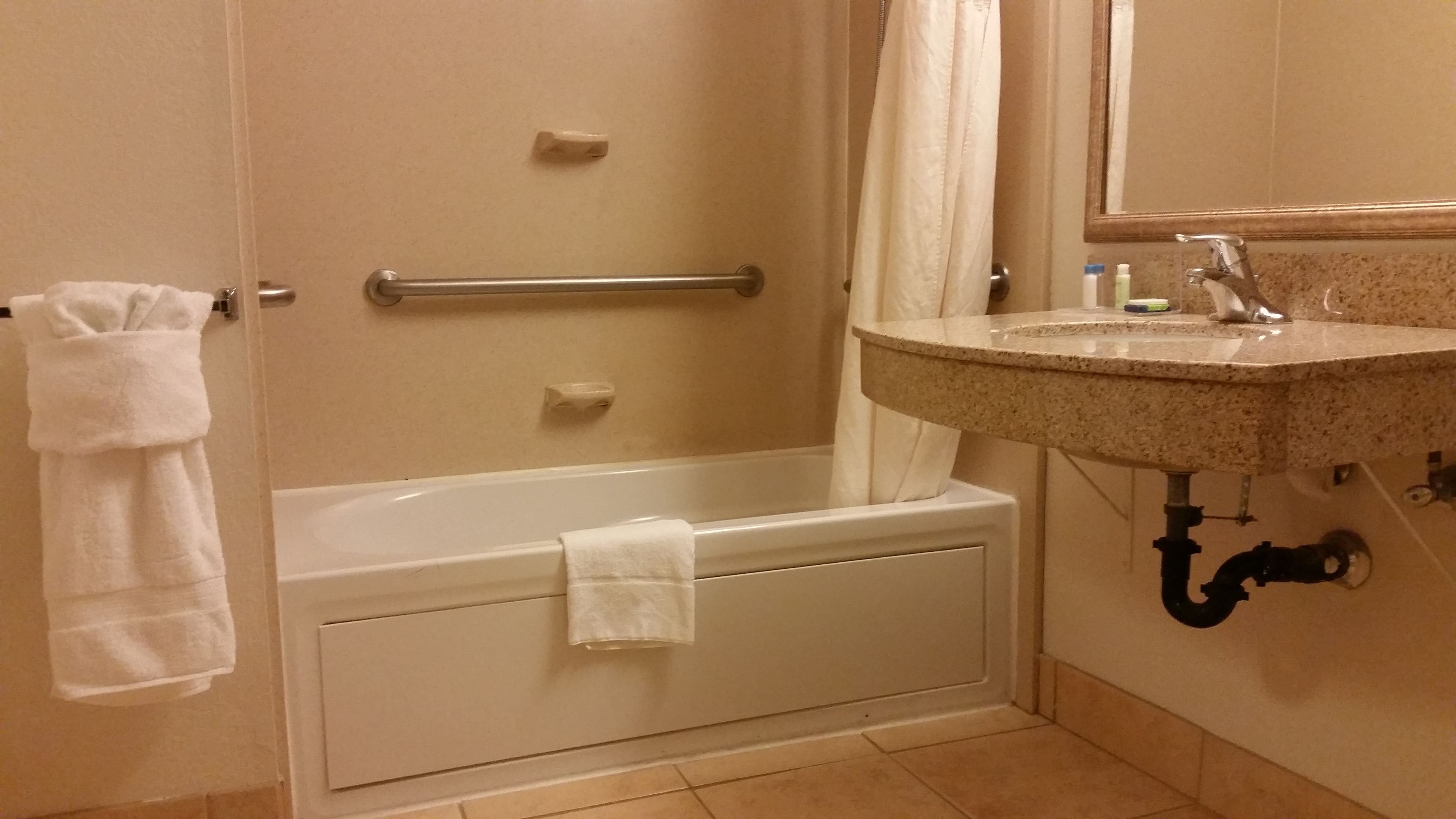 Une salle de bain avec une baignoire, un lavabo et un miroir.