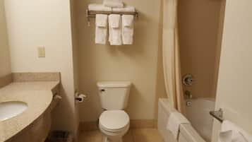 A bathroom with a toilet, sink, and bathtub. There are towels hanging on a rack above the toilet.