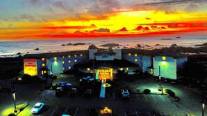 A hotel with a central entrance, parking lot, and ocean view.
