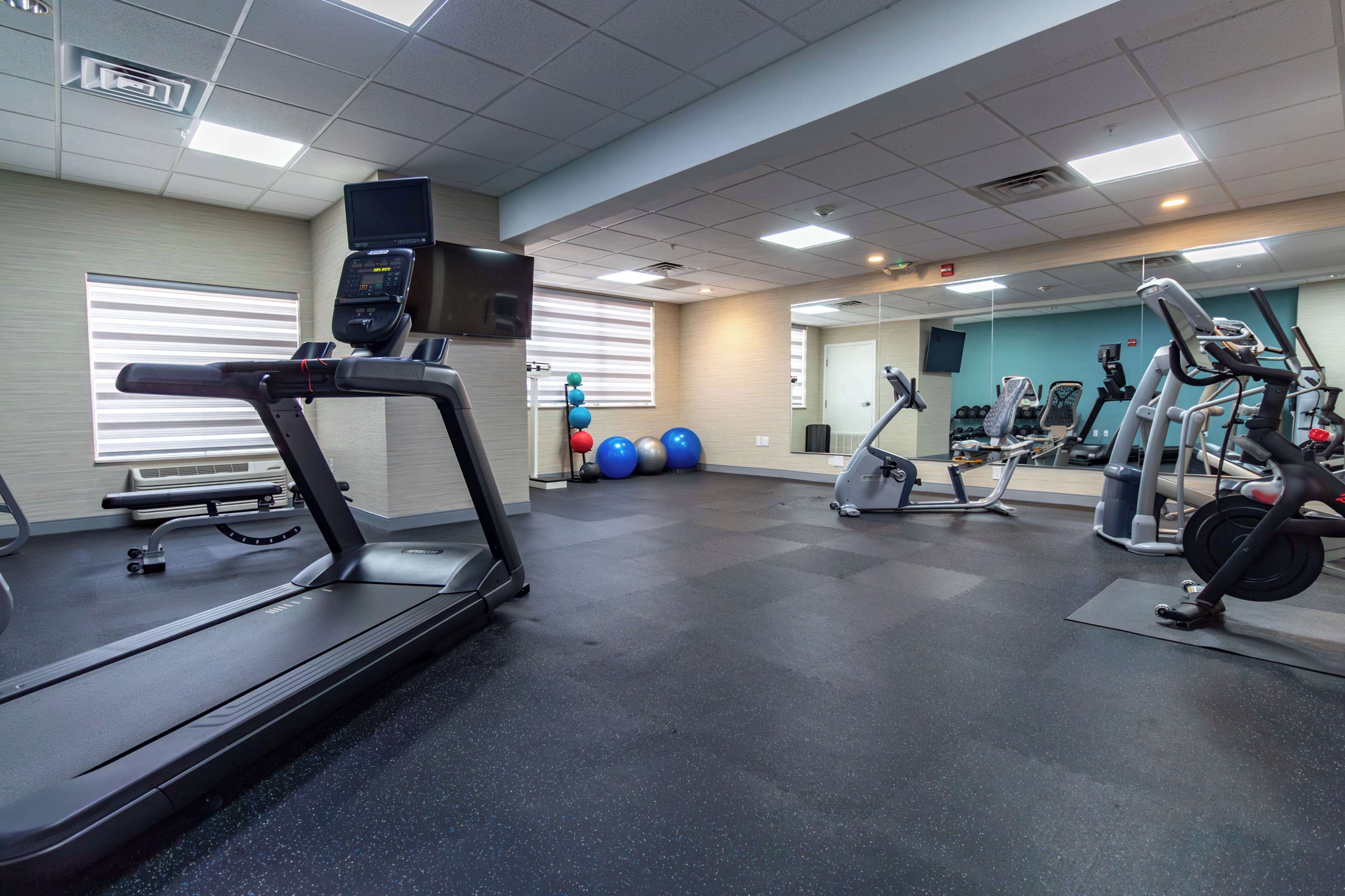 A gym with treadmills, stationary bikes, and exercise balls.