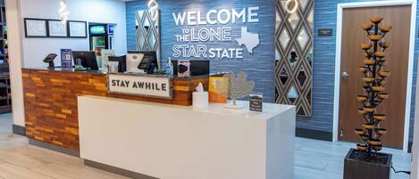 A reception desk with a "WELCOME TO THE LONE STAR STATE" sign, a "STAY WHILE" sign, and a "Not a Hotel" sign.