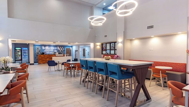 Amplio espacio interior con varias mesas y sillas, un mostrador de recepción y una zona de bar.