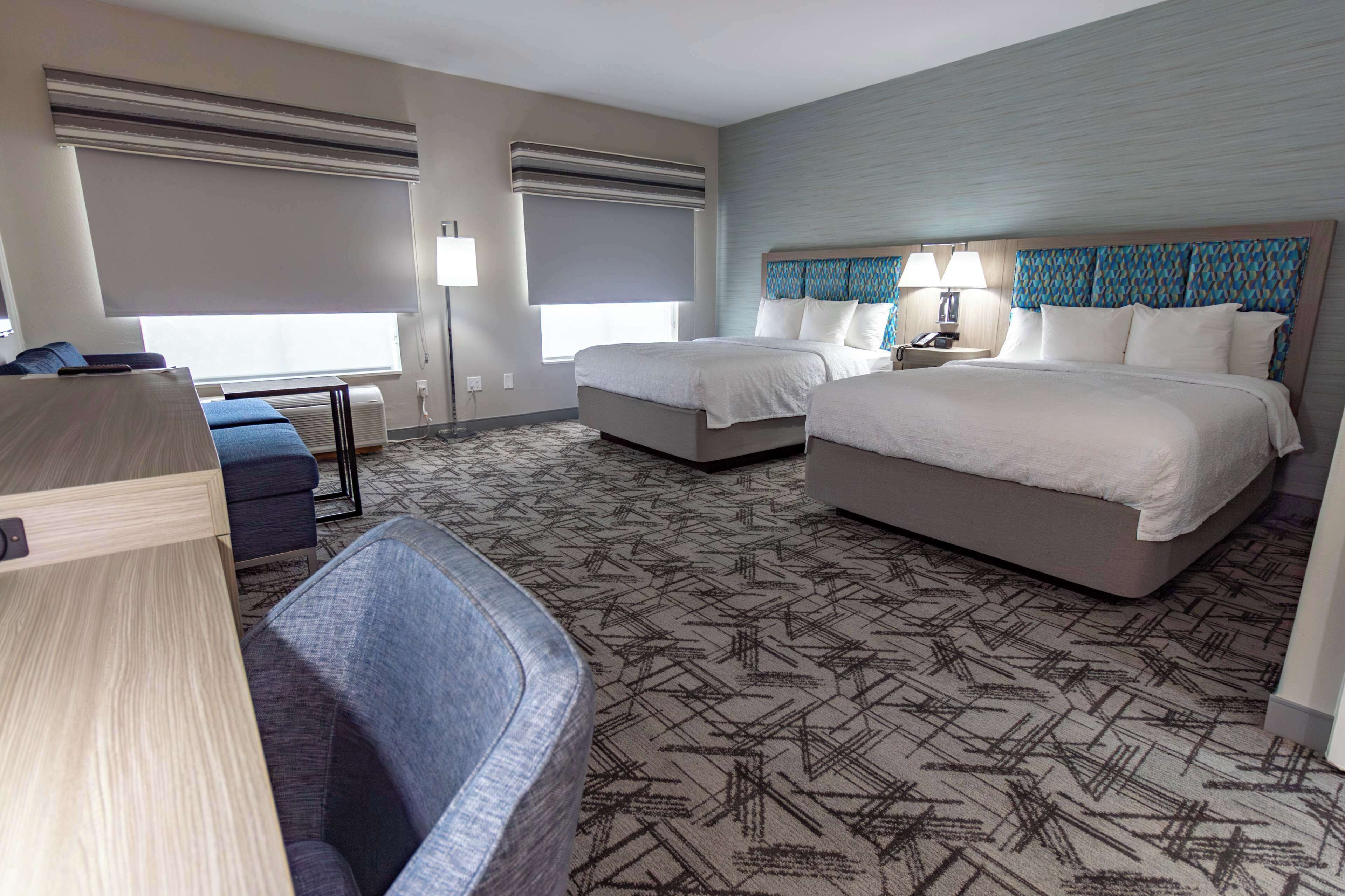 A hotel room with two beds, a desk, and a seating area.