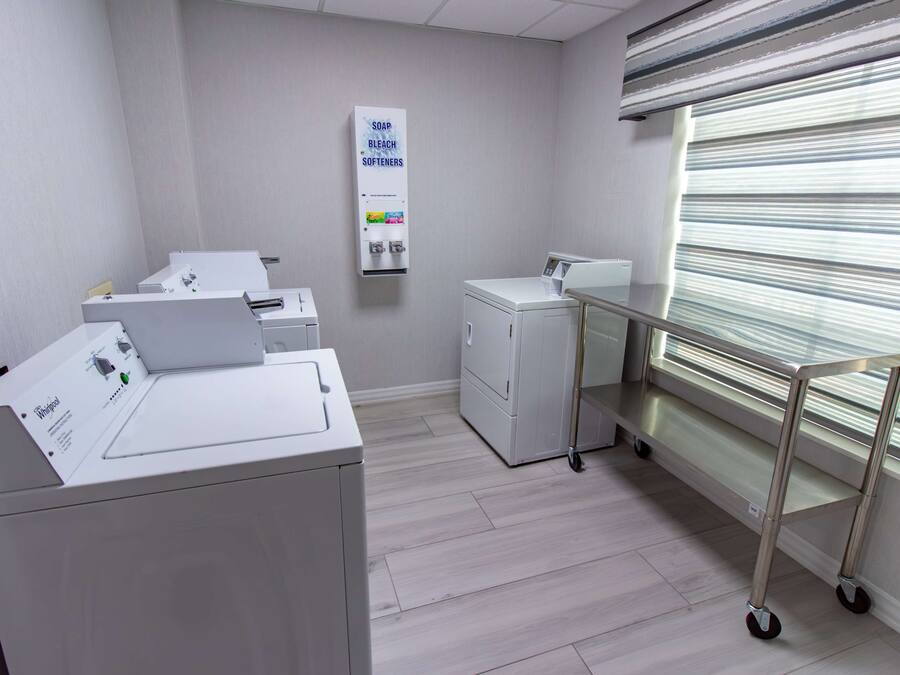 A laundry area with a washing machine, dryer, and a soap dispenser on the wall.