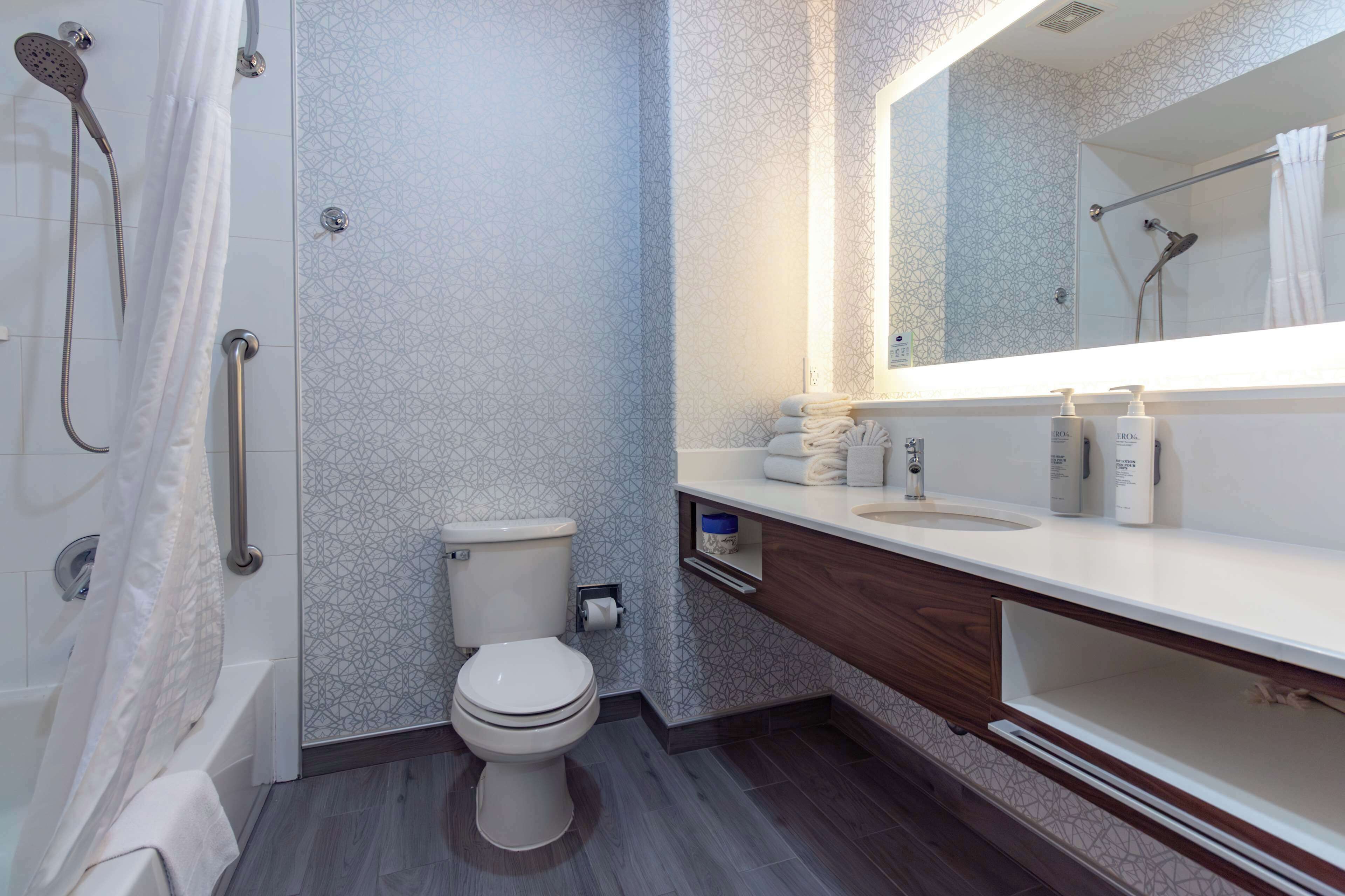 A modern bathroom with a shower, toilet, and vanity.