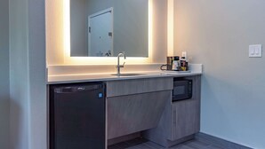 Un baño moderno con lavamanos integrado, un espejo, un lavavajillas y un microondas.