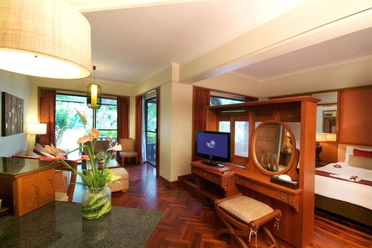 A hotel room with a wooden desk, television, and a large mirror.