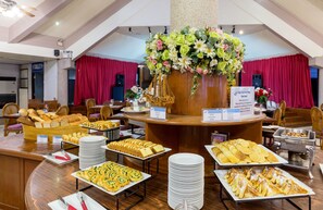 A buffet setup with various food items and a floral centerpiece.