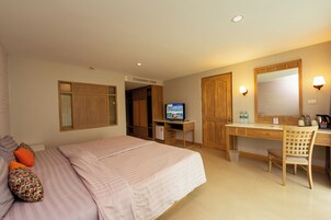 Una camera d'albergo con un letto, una scrivania, una sedia, televisione, armadio e uno specchio.
