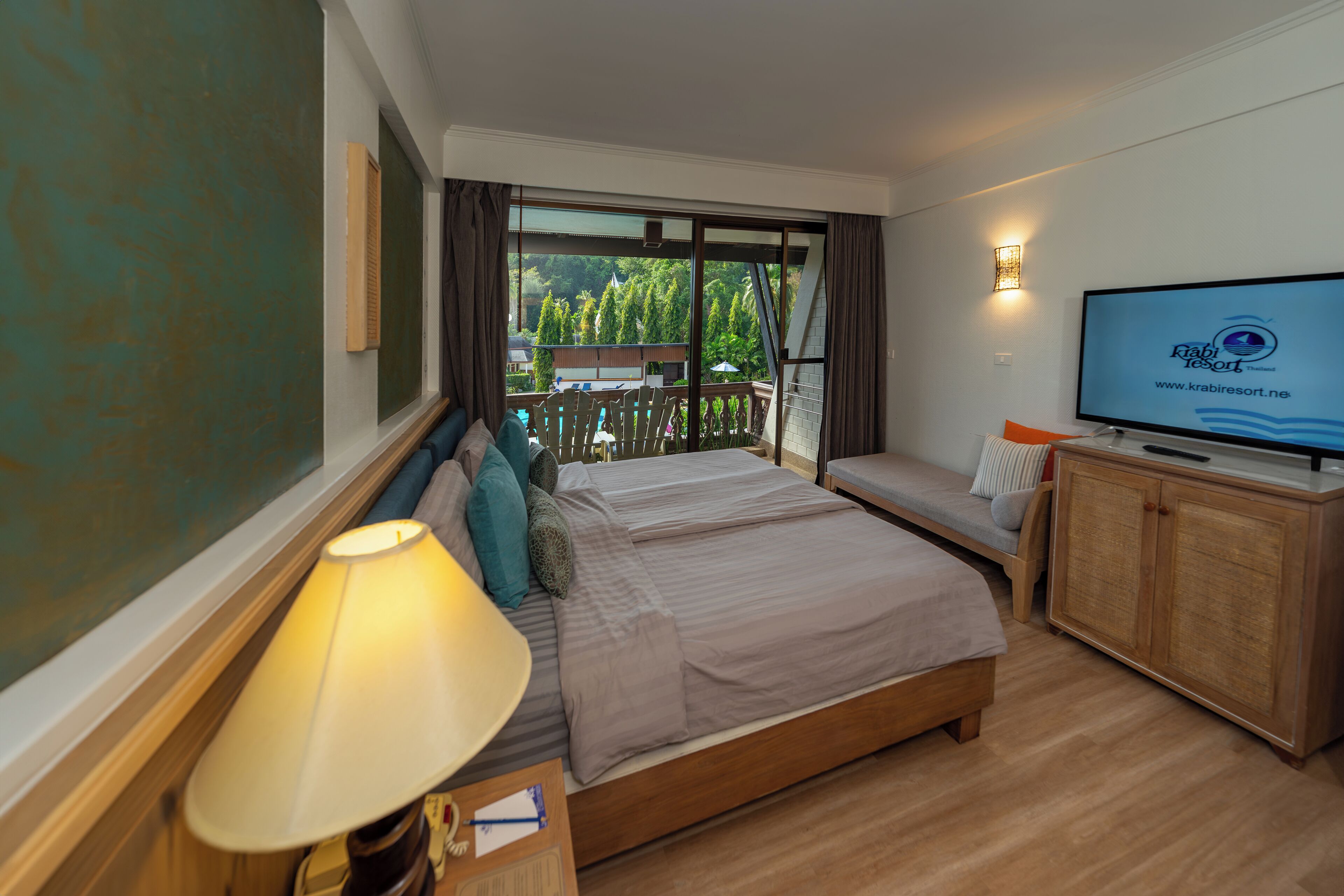 A hotel room with a bed, a TV, a desk, and a view of the outdoors.
