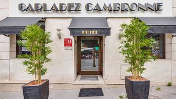 Exterior do hotel Carladez Cambronne com placa indicando que é um hotel.