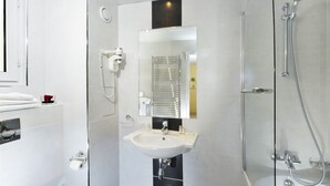 A modern bathroom with a glass-enclosed shower, a white sink, and a mirror above the sink. - Hotel Carladez Cambronne (Paris)