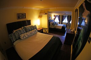 Une chambre d’hôtel avec un grand lit, une table de chevet avec une lampe, un petit bureau et un miroir.