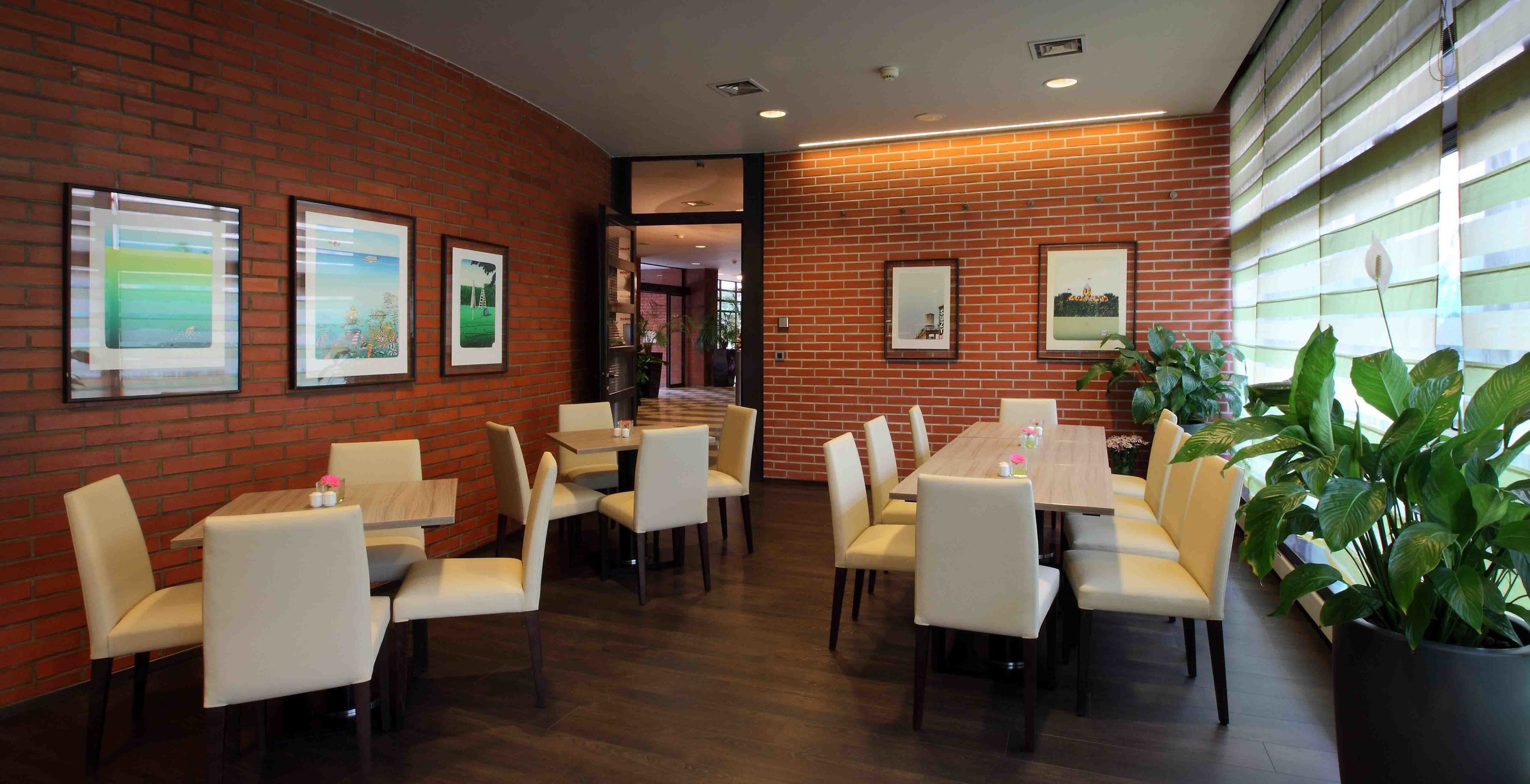 A restaurant with brick walls, framed pictures, and a mix of booth and table seating.