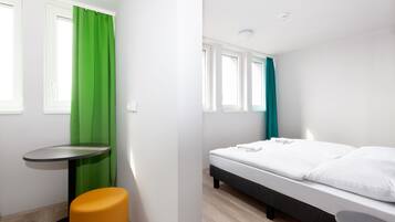 Una habitación moderna con una cama, una mesita y un taburete.