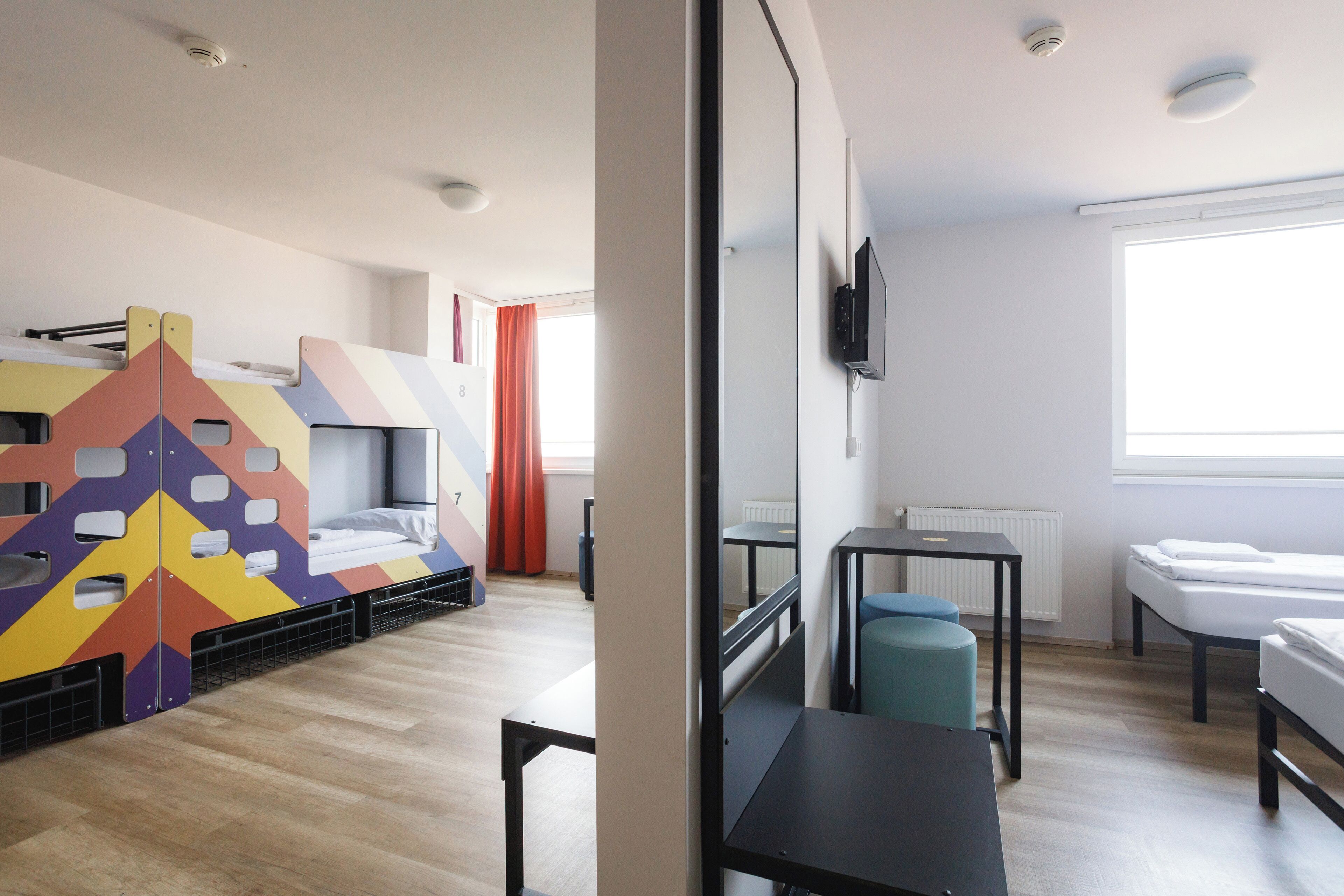 Een hotelkamer met stapelbedden, een bureau, een stoel en een televisie.