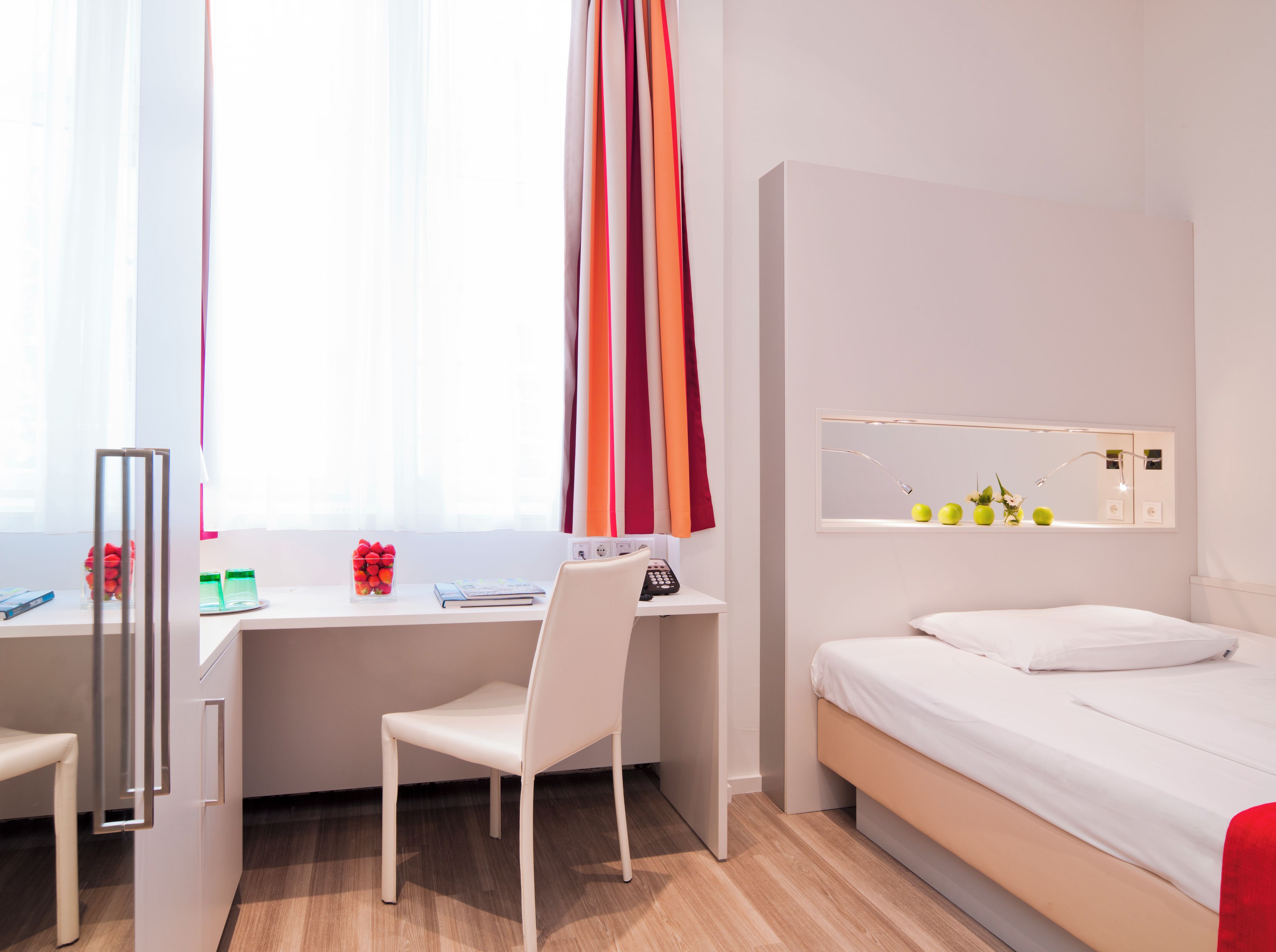 Een moderne hotelkamer met een bureau, stoel en bed.