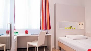 Een moderne hotelkamer met een bureau, stoel en bed.