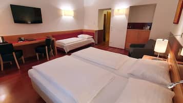 Ein Hotelzimmer mit zwei Betten, einem Schreibtisch, einem Stuhl, einem Fernseher und einer Küchenzeile.