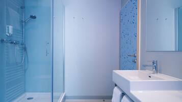 Een moderne badkamer met een douchecabine van glas, een witte wastafel en een spiegel.