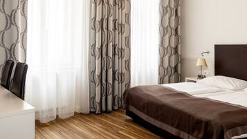 Ein Hotelzimmer mit Bett, Nachttisch, Lampe und Stuhl.