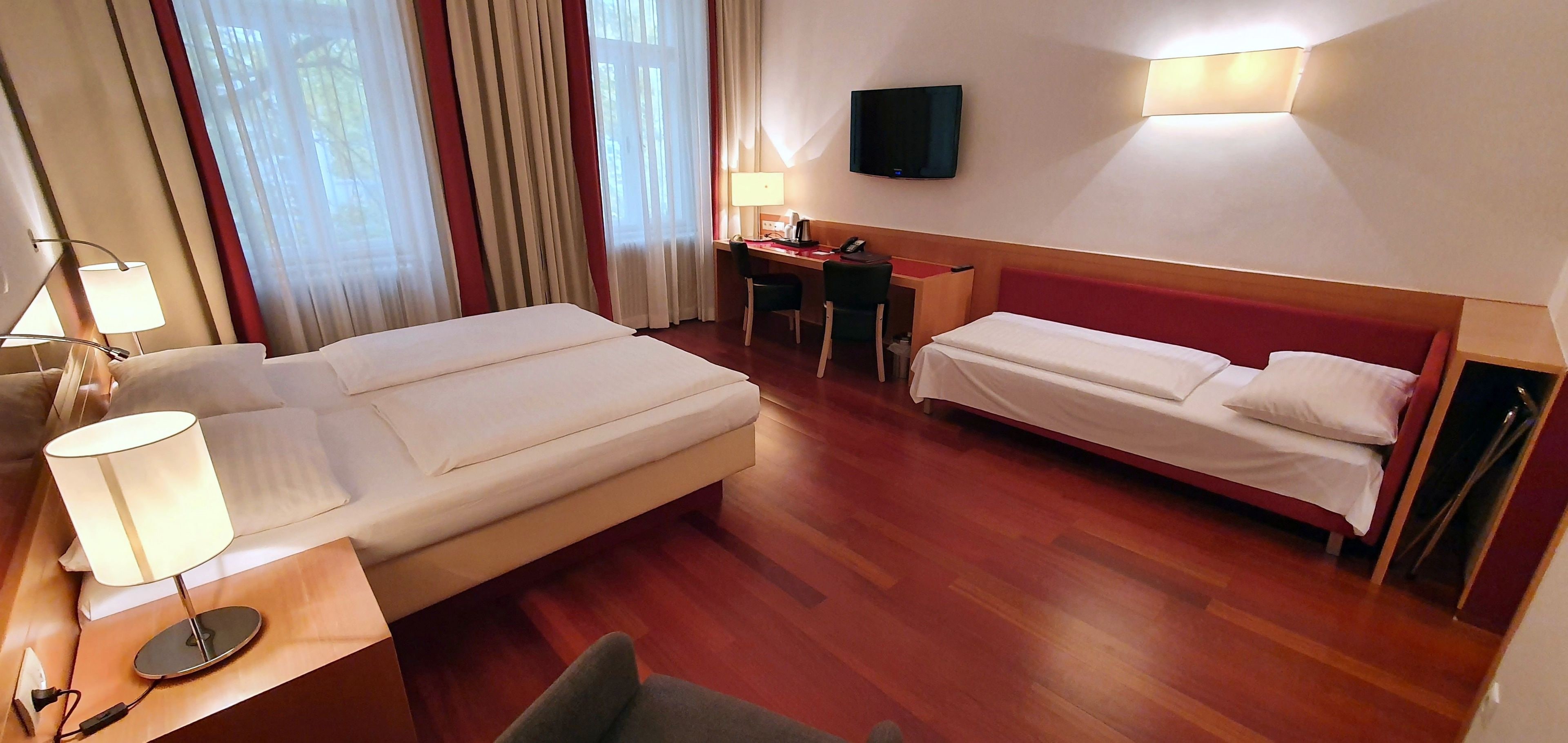 Ein Hotelzimmer mit einem Bett, einem Schreibtisch, einem Stuhl, einem Fernseher und einer Lampe.