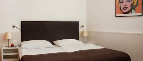 Una habitación de hotel con una cama, dos lámparas de noche, una mesita de noche y un cuadro en la pared.