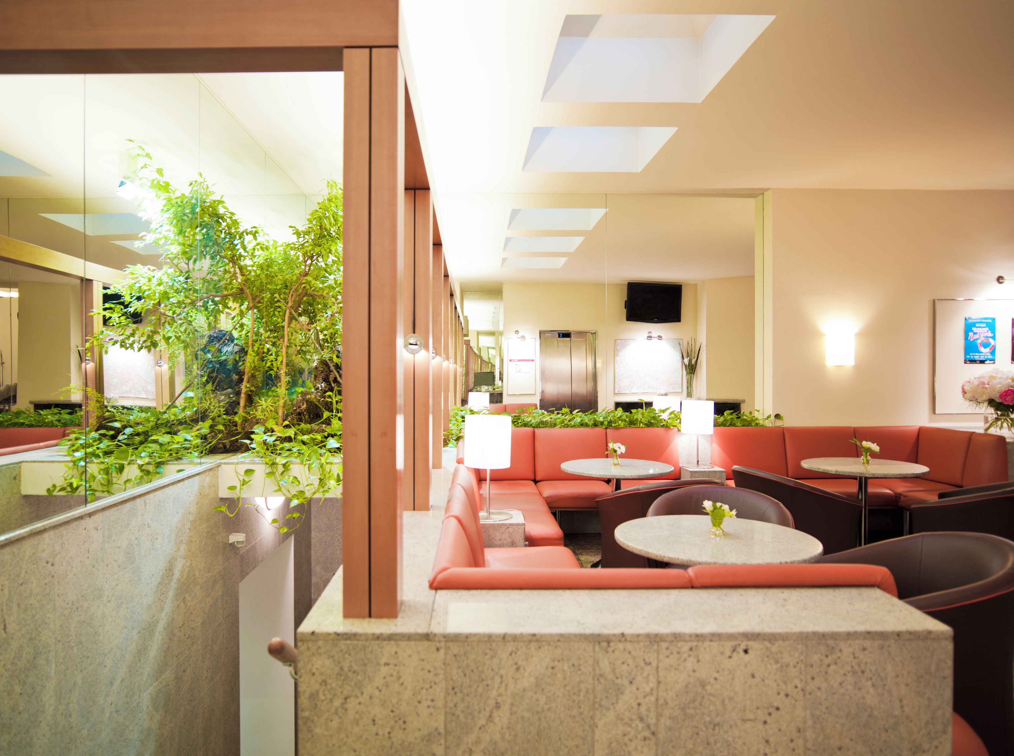 Um hall de hotel com área de estar, balcão de recepção e televisão na parede.