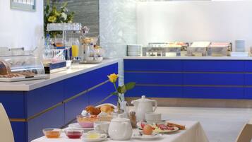 Un bufé de desayuno con diversos alimentos y un florero con una flor amarilla sobre una mesa.