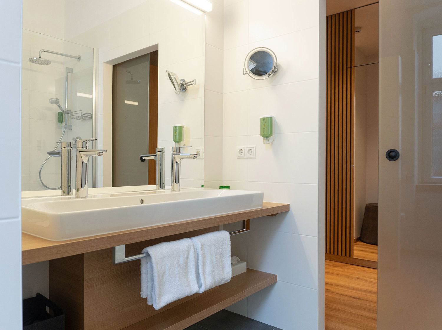Een moderne badkamer met een grote spiegel, een wastafel en een douche.